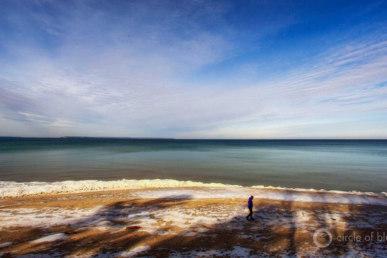 As the ground begins to thaw from winter, a local Michigander walks along the coast of Lake Michiga