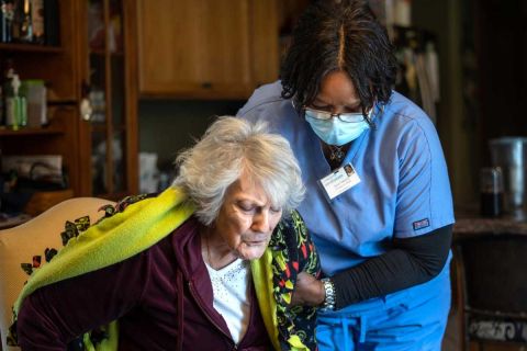 Excellacare Care Provider Sarah Sutherlin helps her client Carmela Palamara, 92, of Brownstown stand up to stretch her legs after the two color and play a game of UNO at Palamara's home on Wednesday, April 14, 2021. 