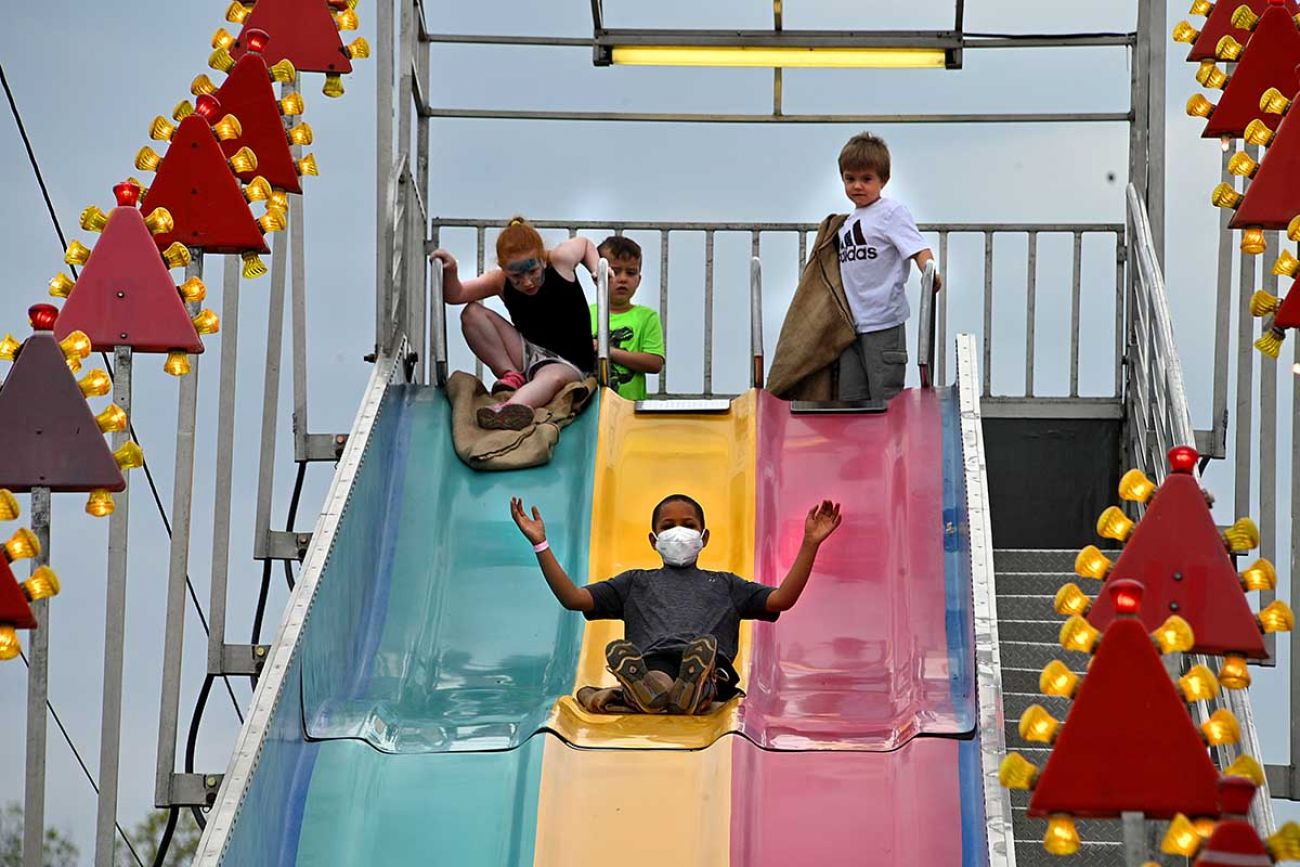 Children – some masked, some not – play on a slide at the Durand Railroad Days Festival