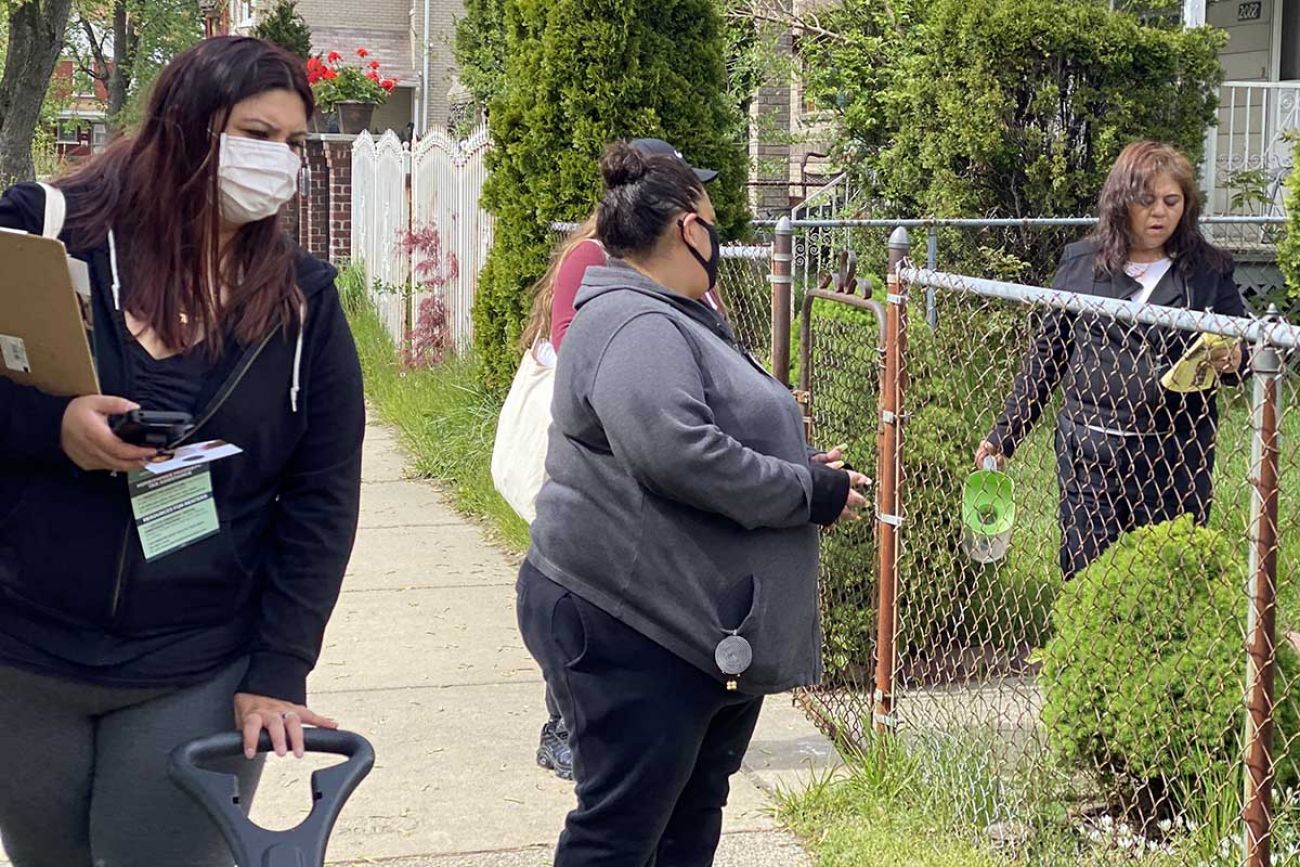 Almadelia Gonzalez, left, and Elizabeth Gonzalez inform a neighborhood resident about COVID-19 vaccination sites in Southwest Detroit.