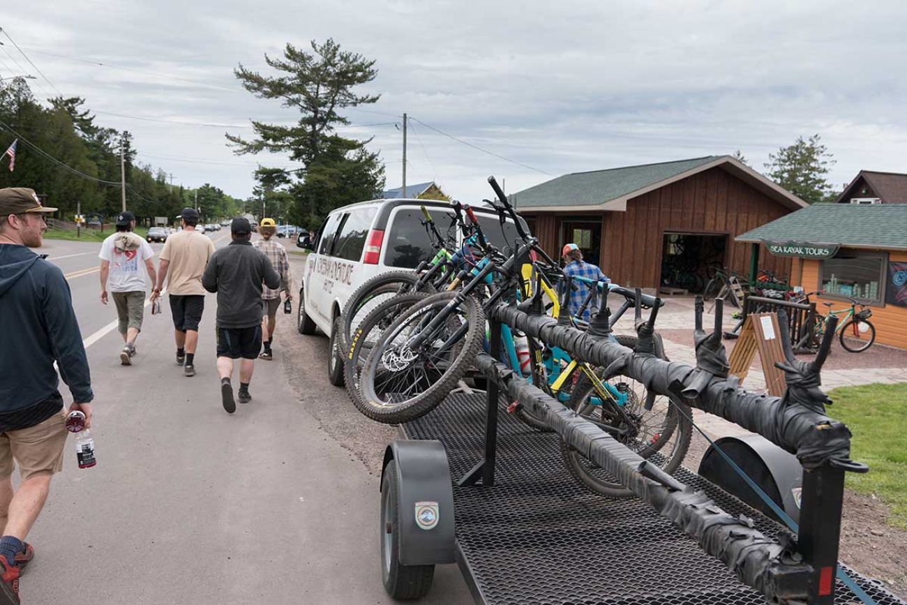 Pedestrians walk by as the Keweenaw Adventure Company shuttle loads up bikes to drive people to the top of Brockway Mountain.