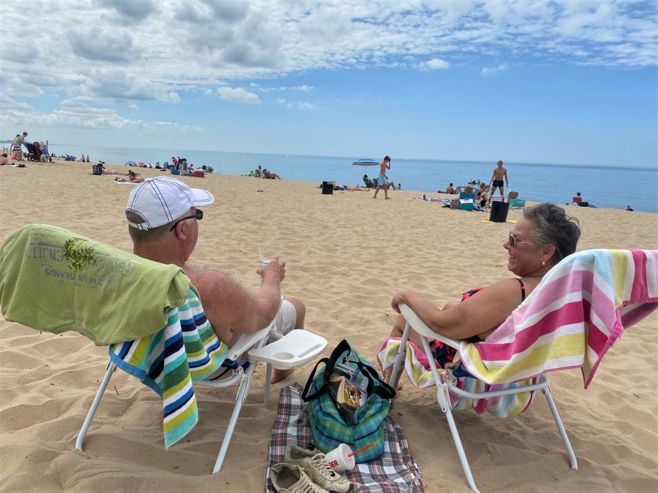 Cary and Lori Gray, seated facing away from the camera, on the beach looking toward the lake