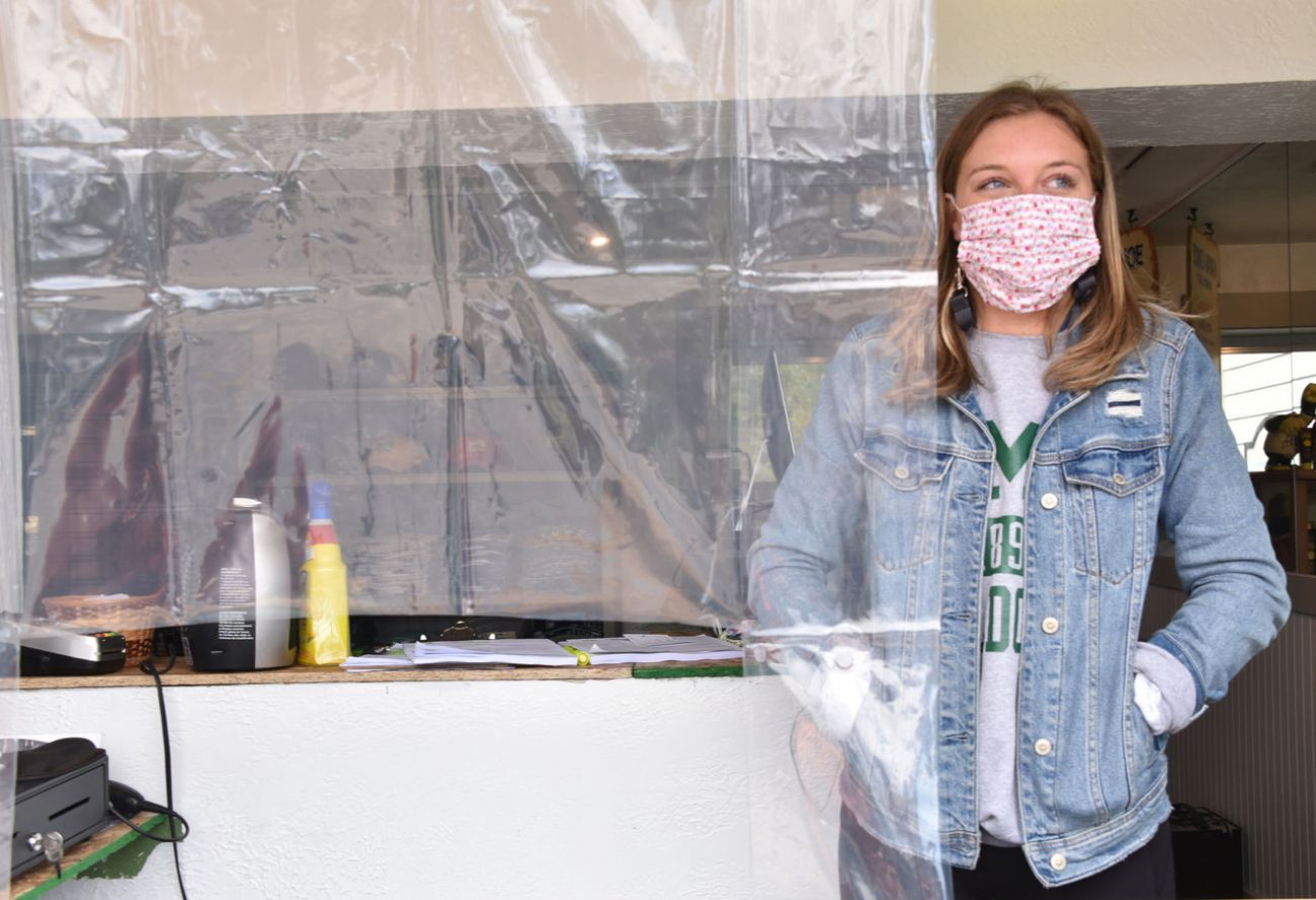 Jess Pershinske, standing with hands in pockets behind a plastic sheet hung from the ceiling