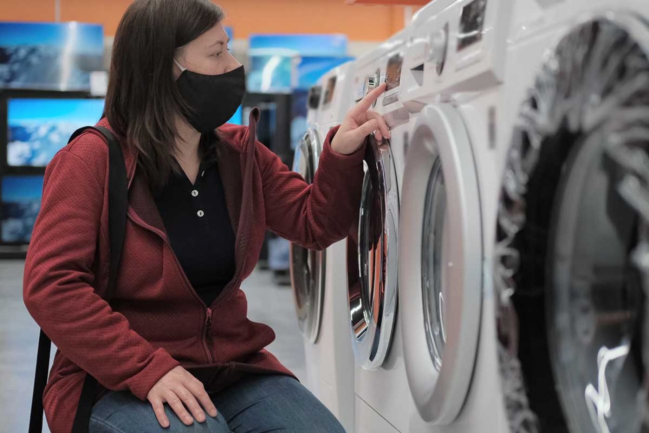 woman in mask looking at washer
