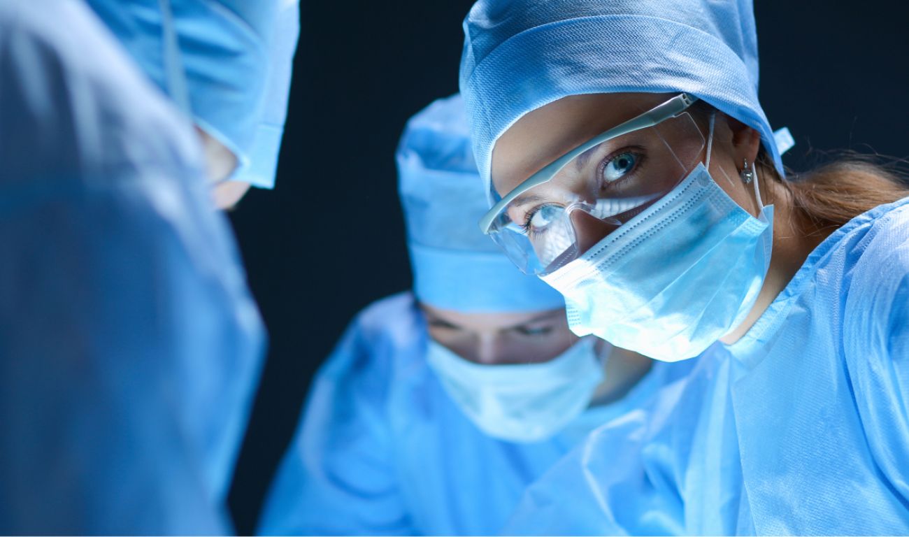 Doctors in scrubs facing toward an off-screen patient.