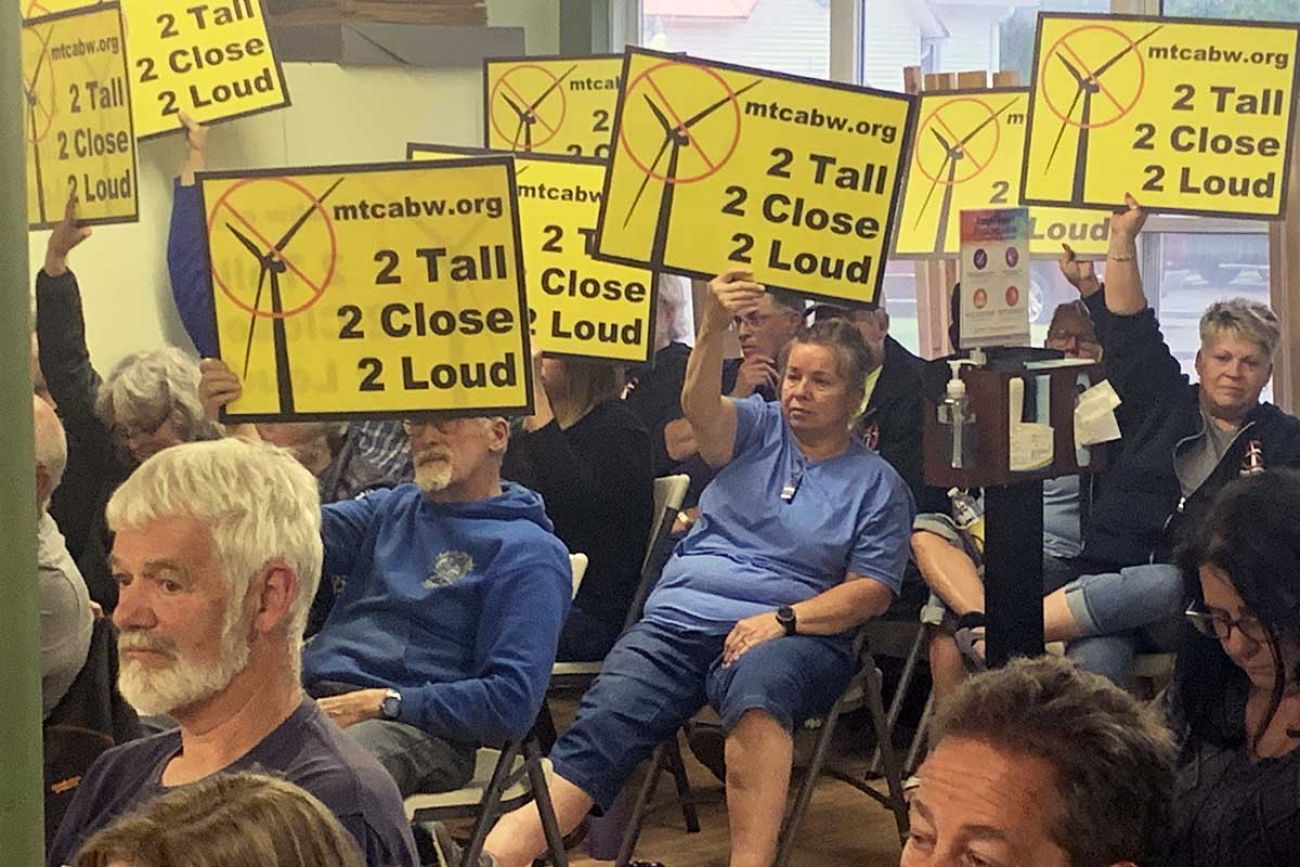 people holding signs against wind tribunes