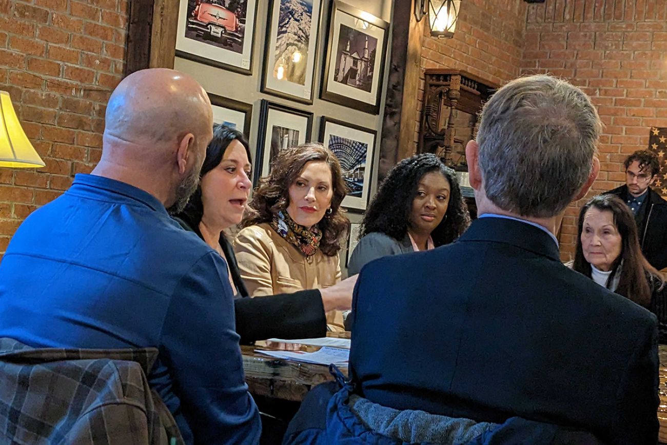 whitmer sitting at a table with other people