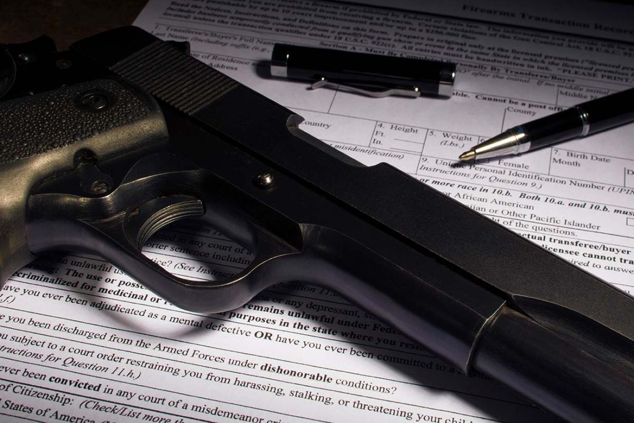 gun with bullets sat on top of paperwork