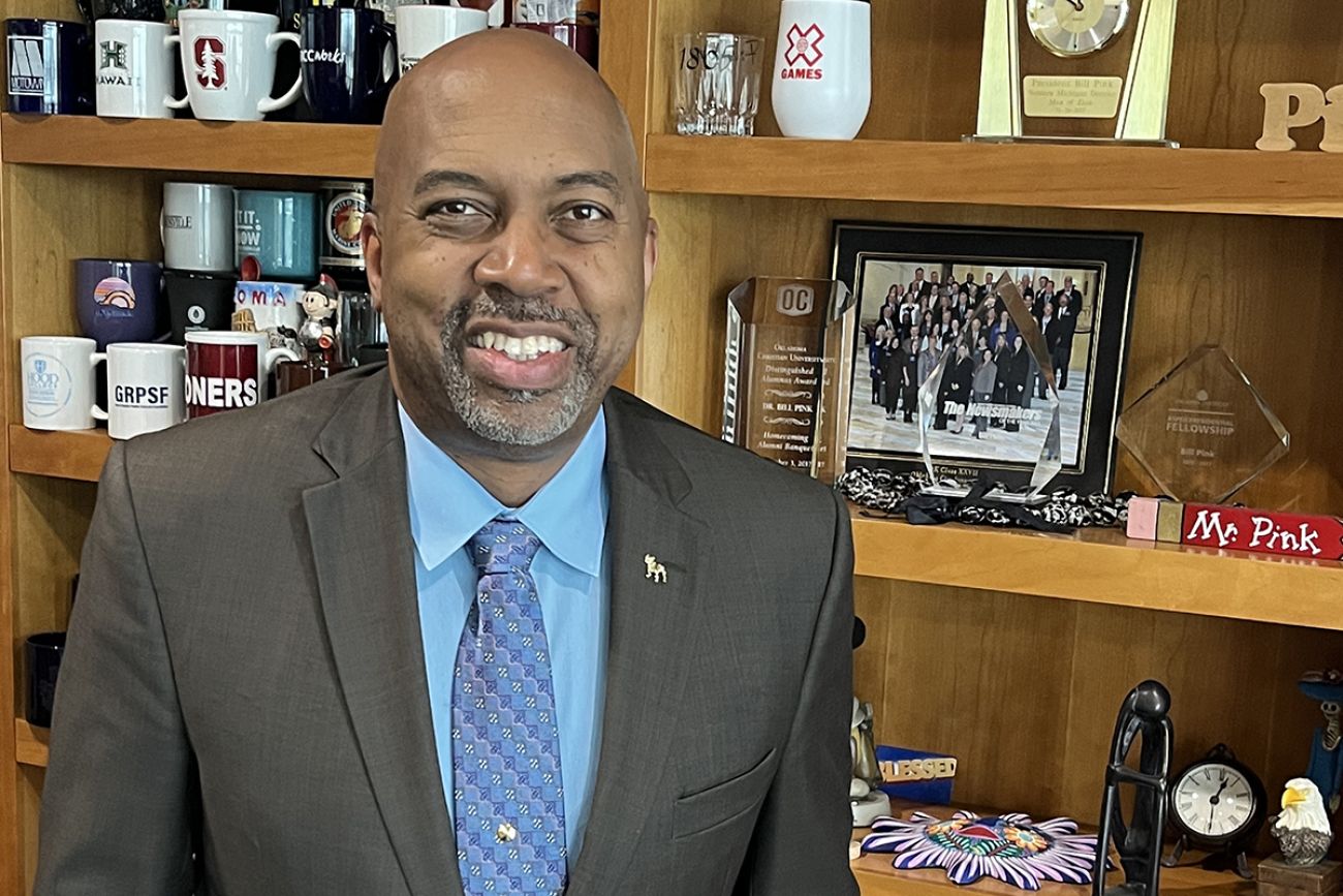 Bill Pink, president of Ferris State University in Big Rapids, standing in front of a shelf