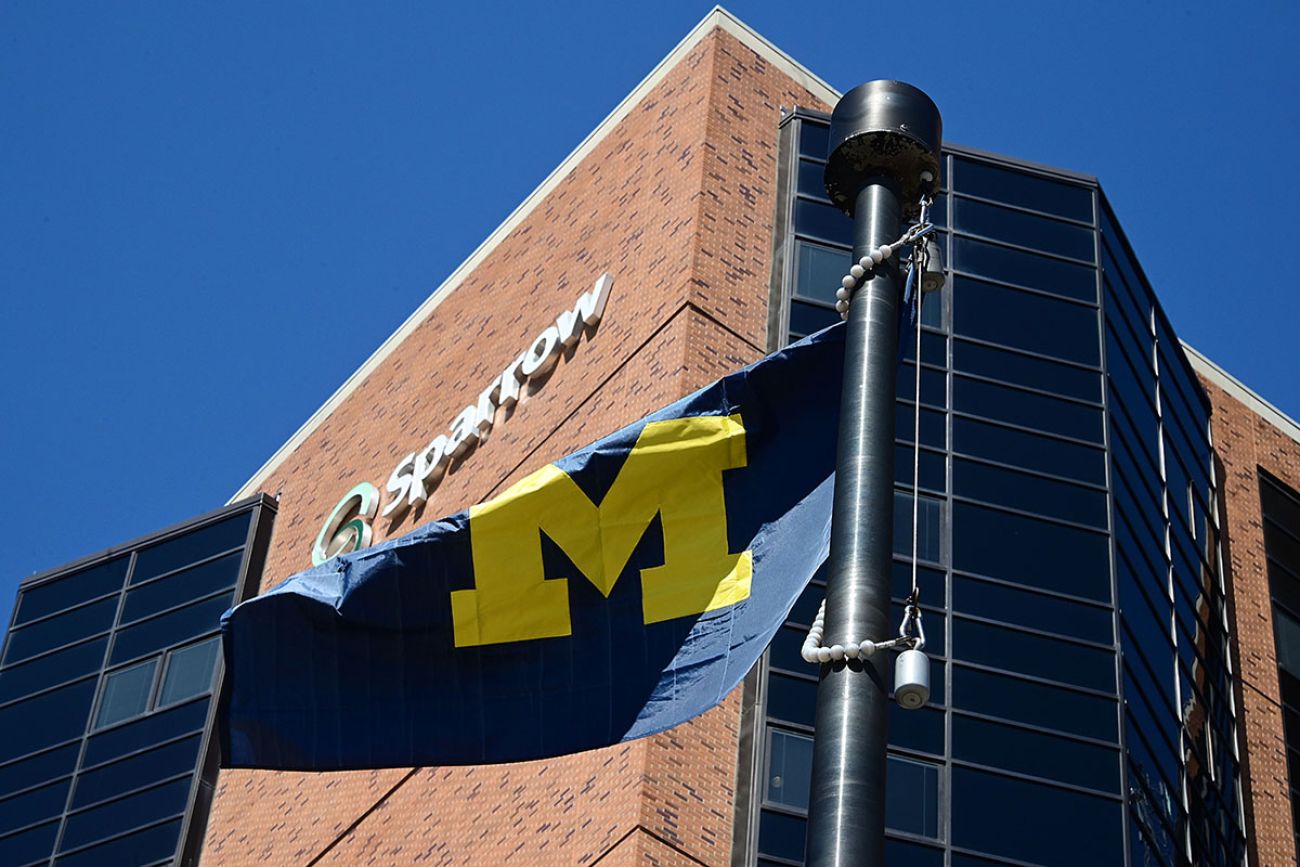 University of Michigan flag in front of Sparrow Health System hospital