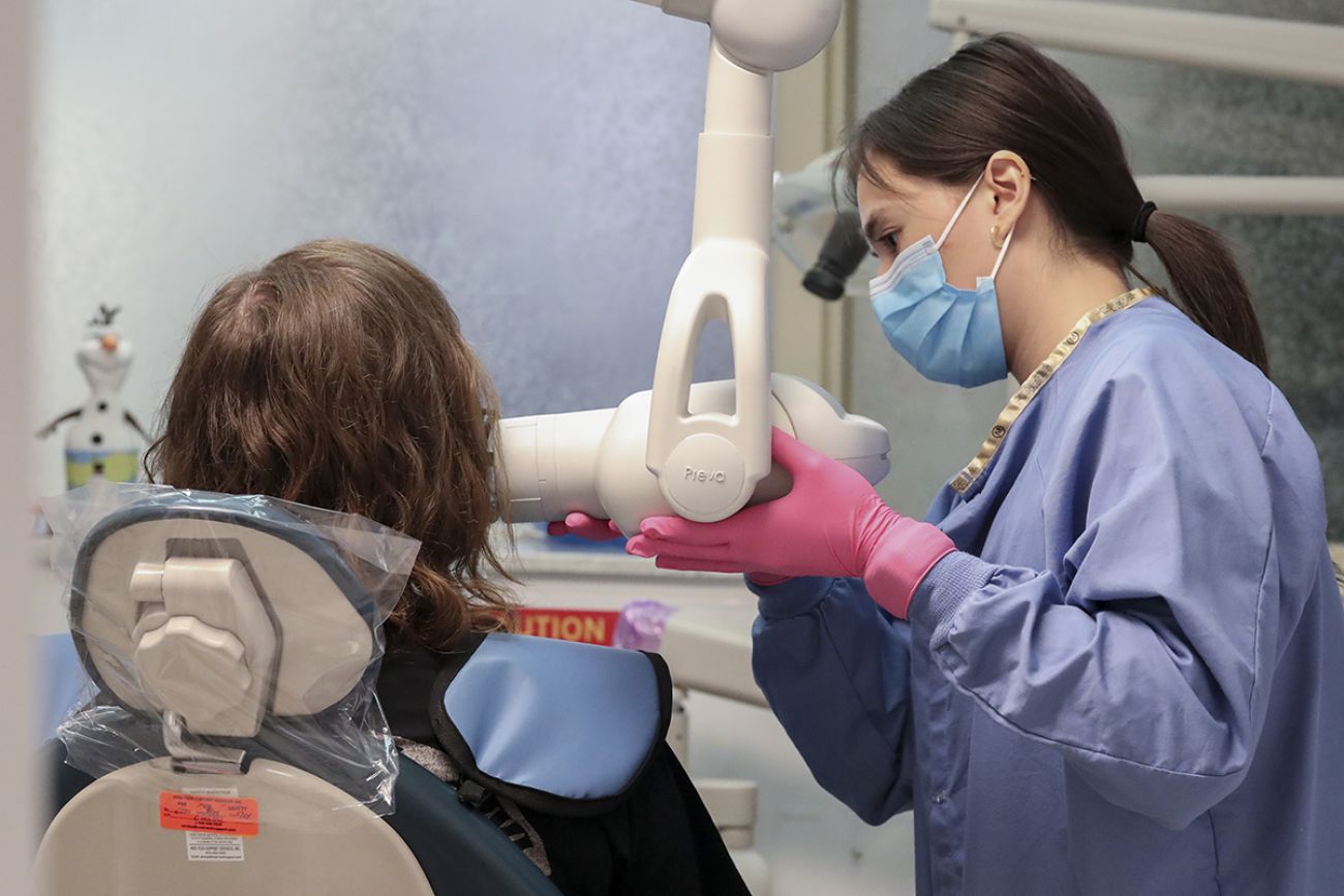 dental assistant preparing an x-ray while someone is sitting in a medical chair