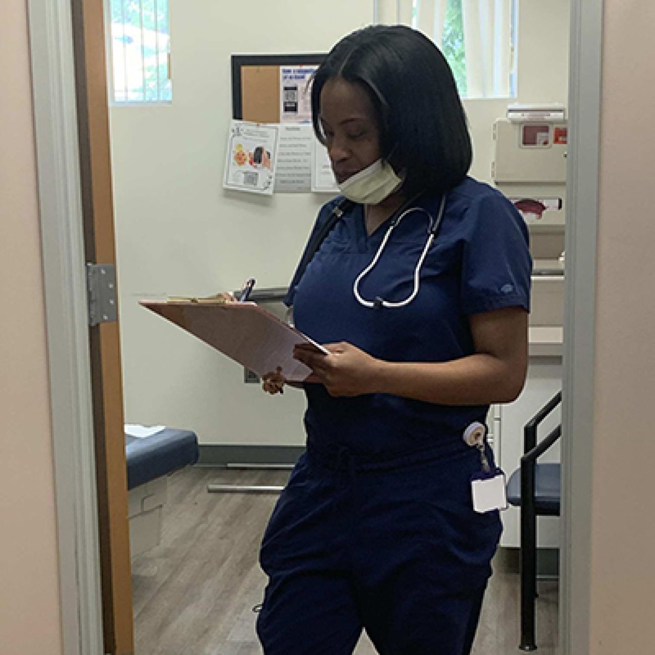 woman in blue scrubs looking at clipboard