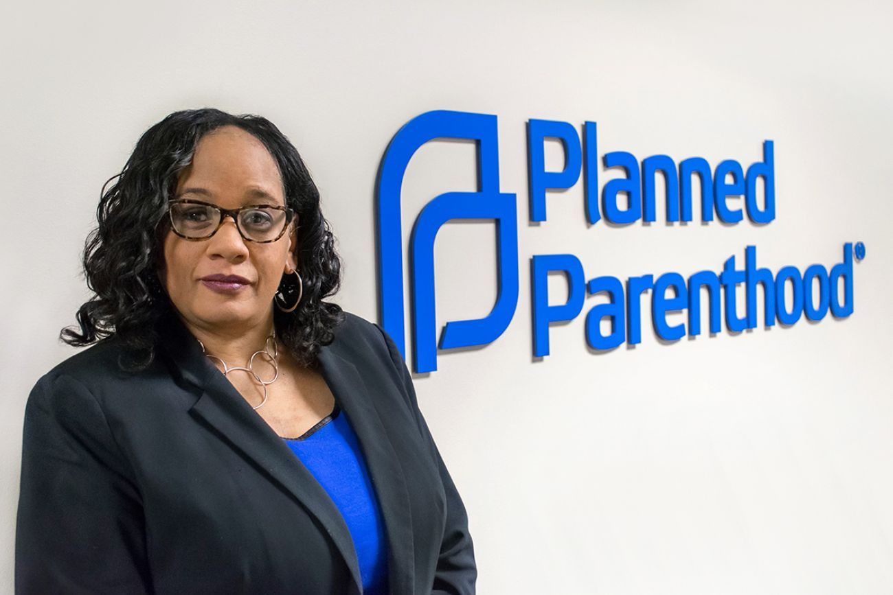 Paula Thornton Greear standing in front of Planned Parenthood sign