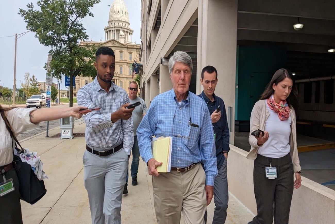 Gerald Clixby walks with reporters holding phones