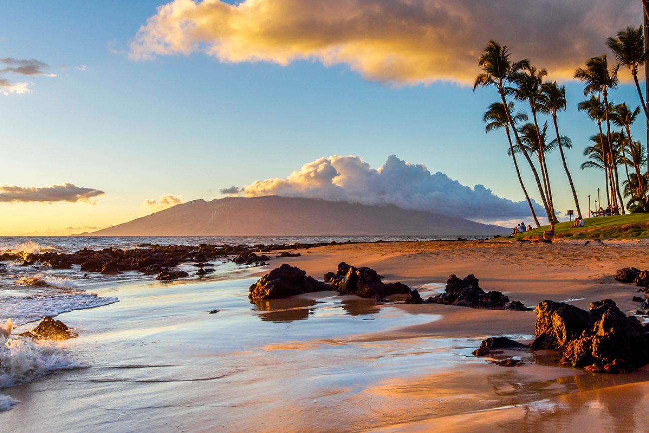 The sunset creates a warm glow on a beach in Maui