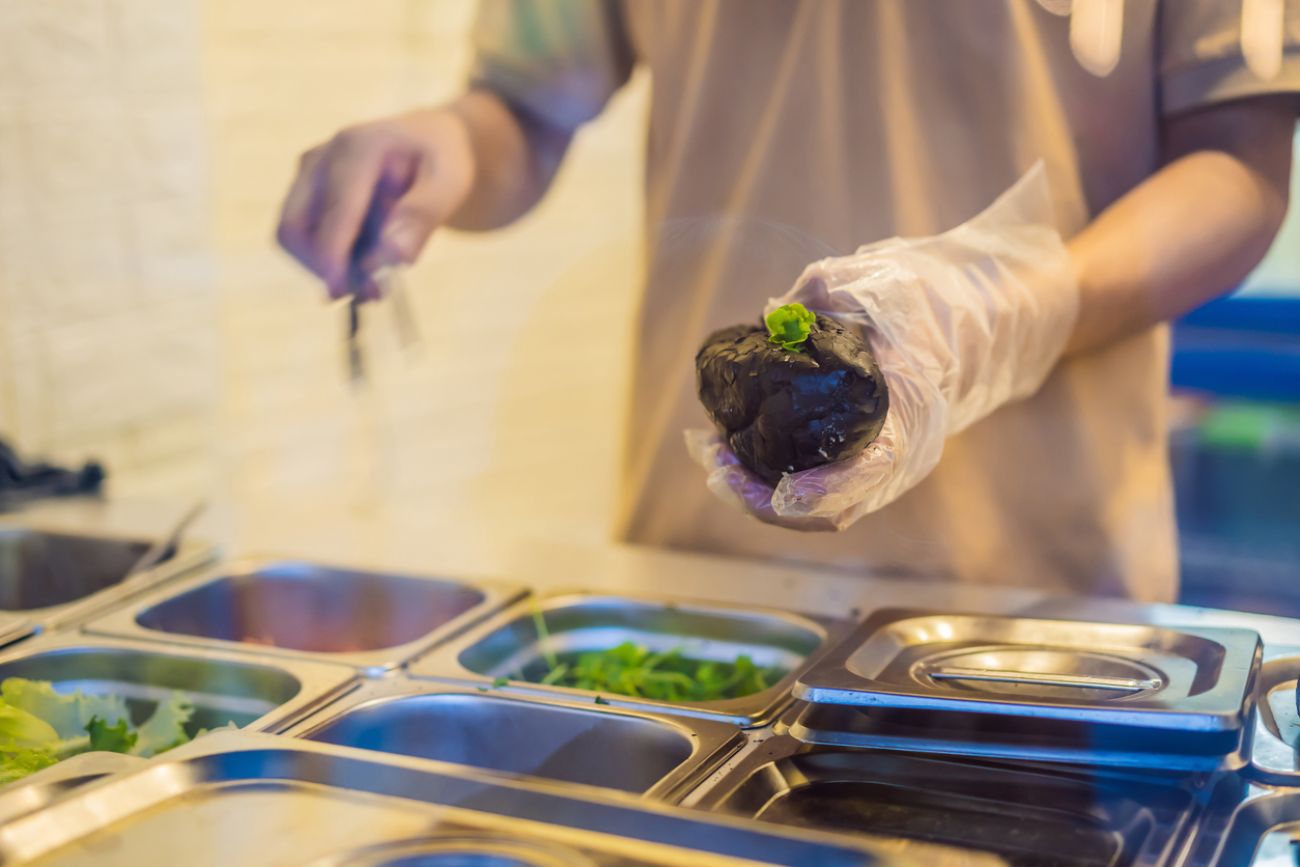 The man is cooking Vietnamese Pork Banh Mi Sandwich in a black baguette.