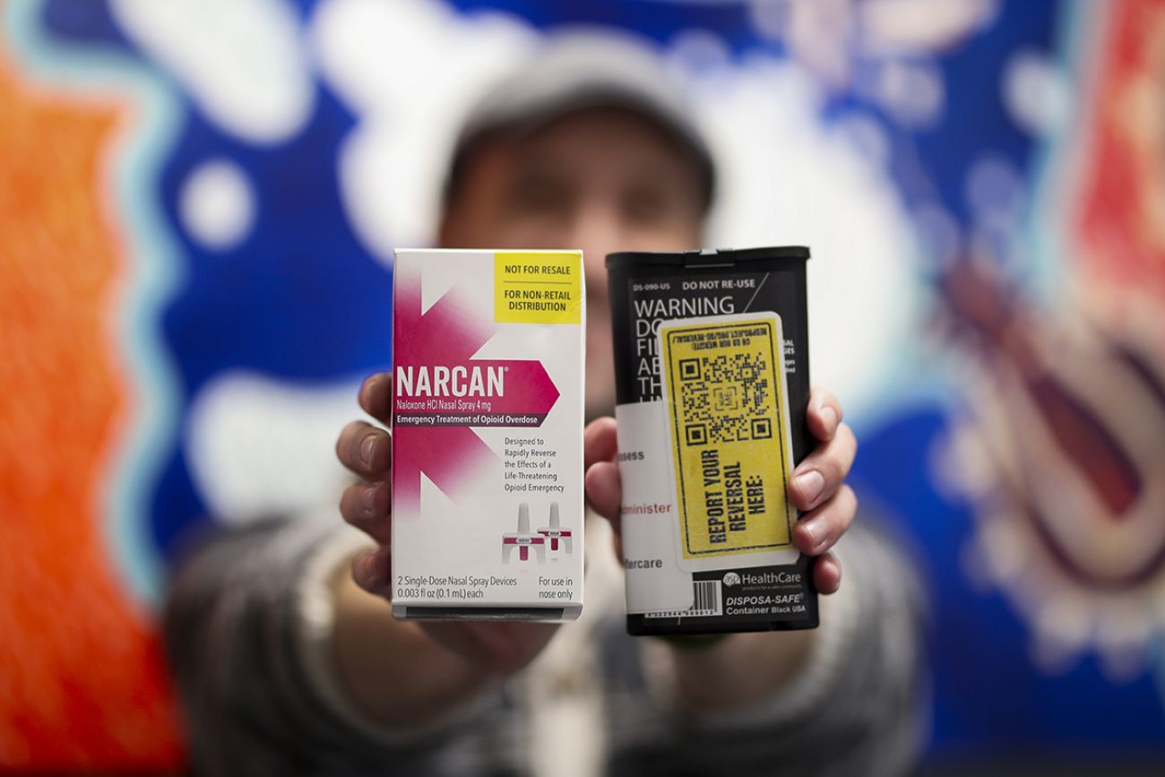 man holds up two naloxone kits