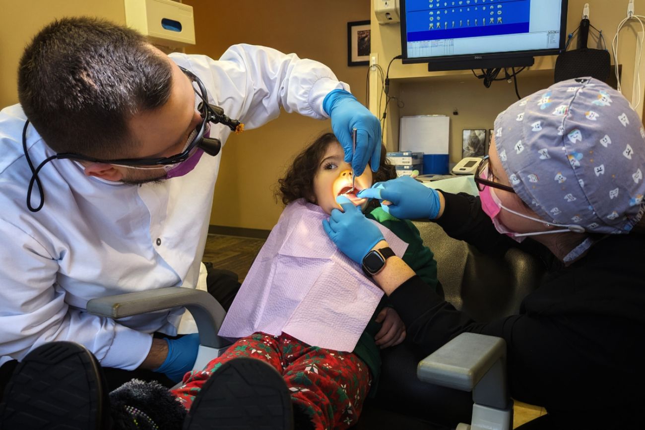 Young girl sits in dental chair with a dentist