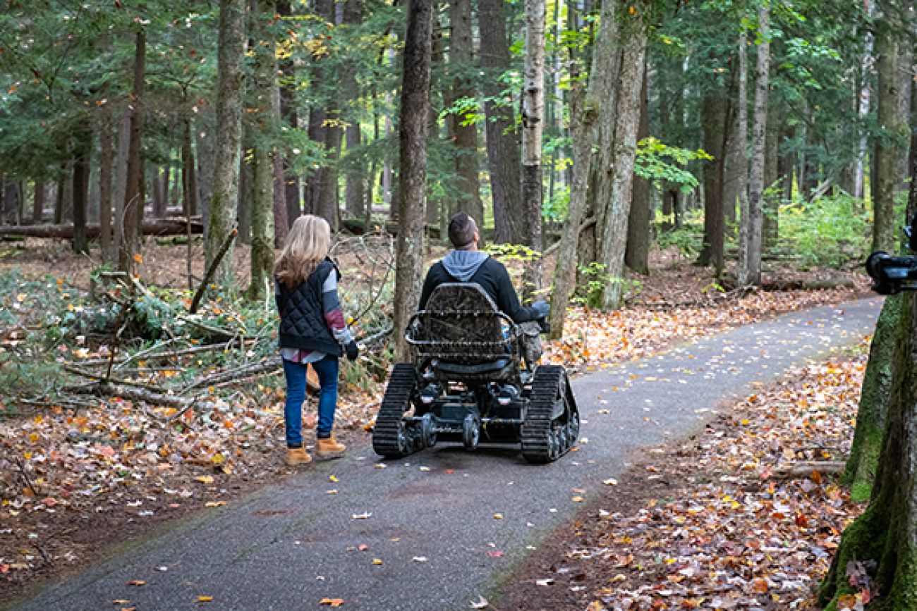 Two people, one in a wheelchair, on a trail.