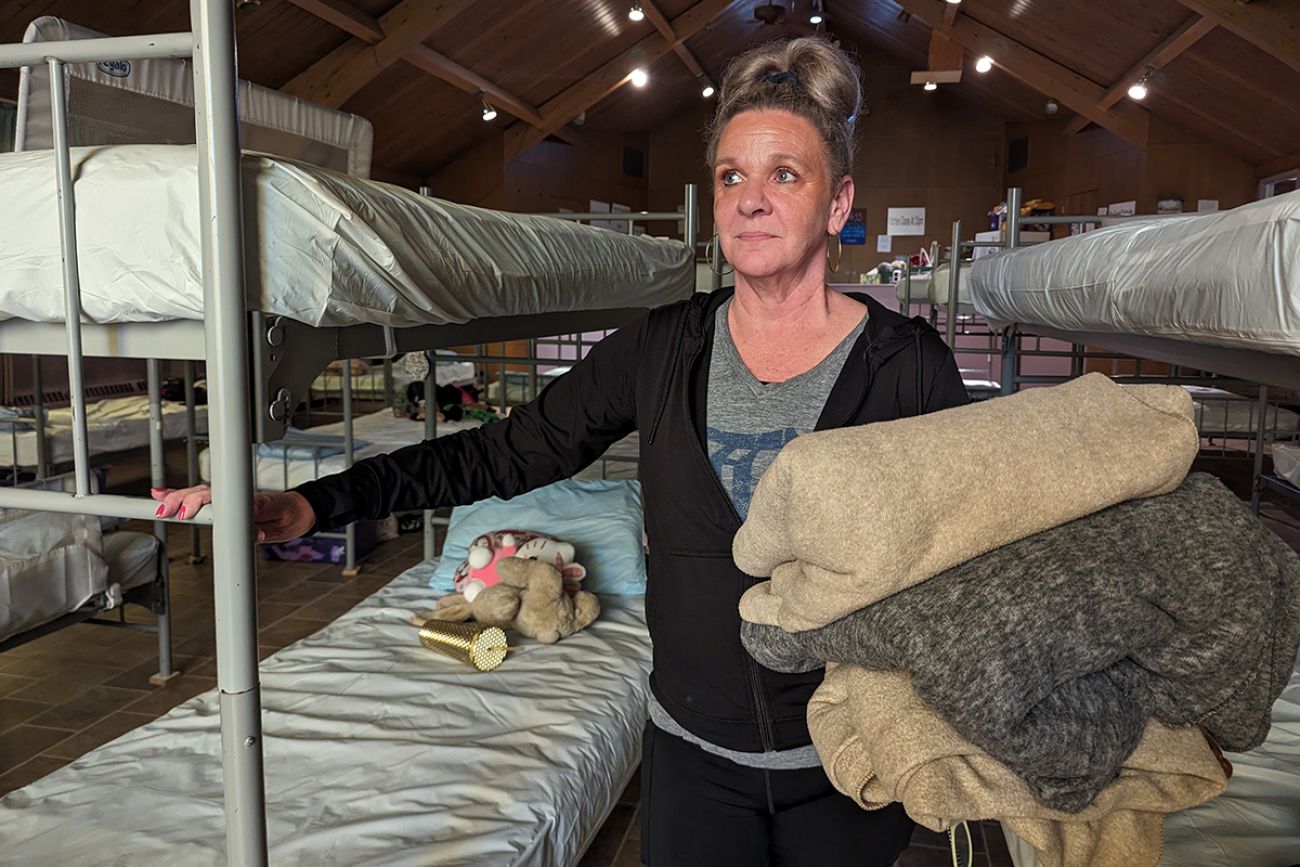 Trish Burgess standing next to a bed in a shelter