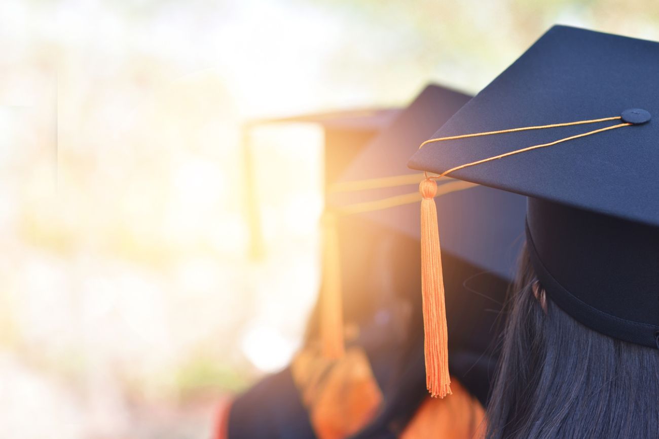  The back image of the graduates wearing a yellow tassel hat