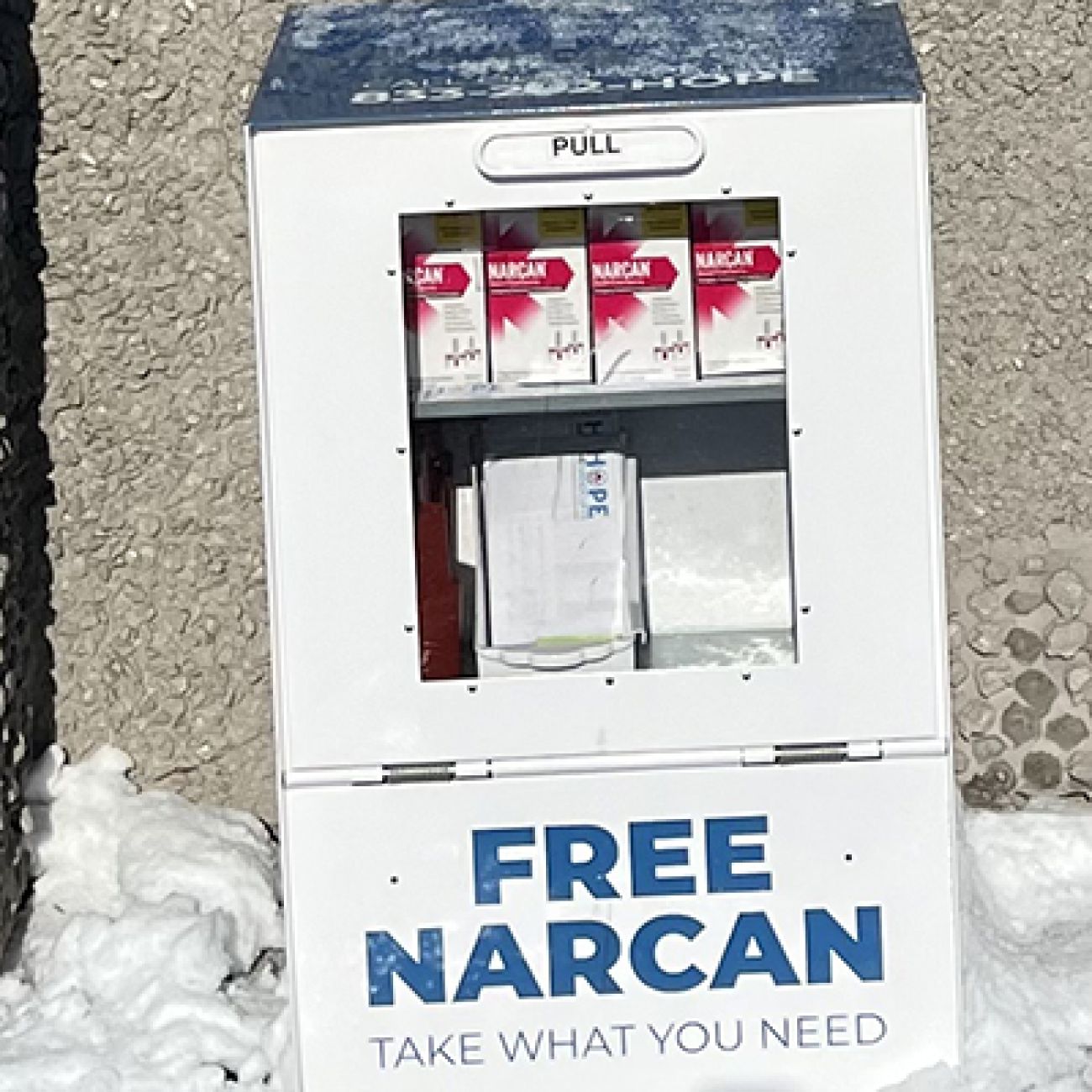 A white old newspaper box that says Free Narcan