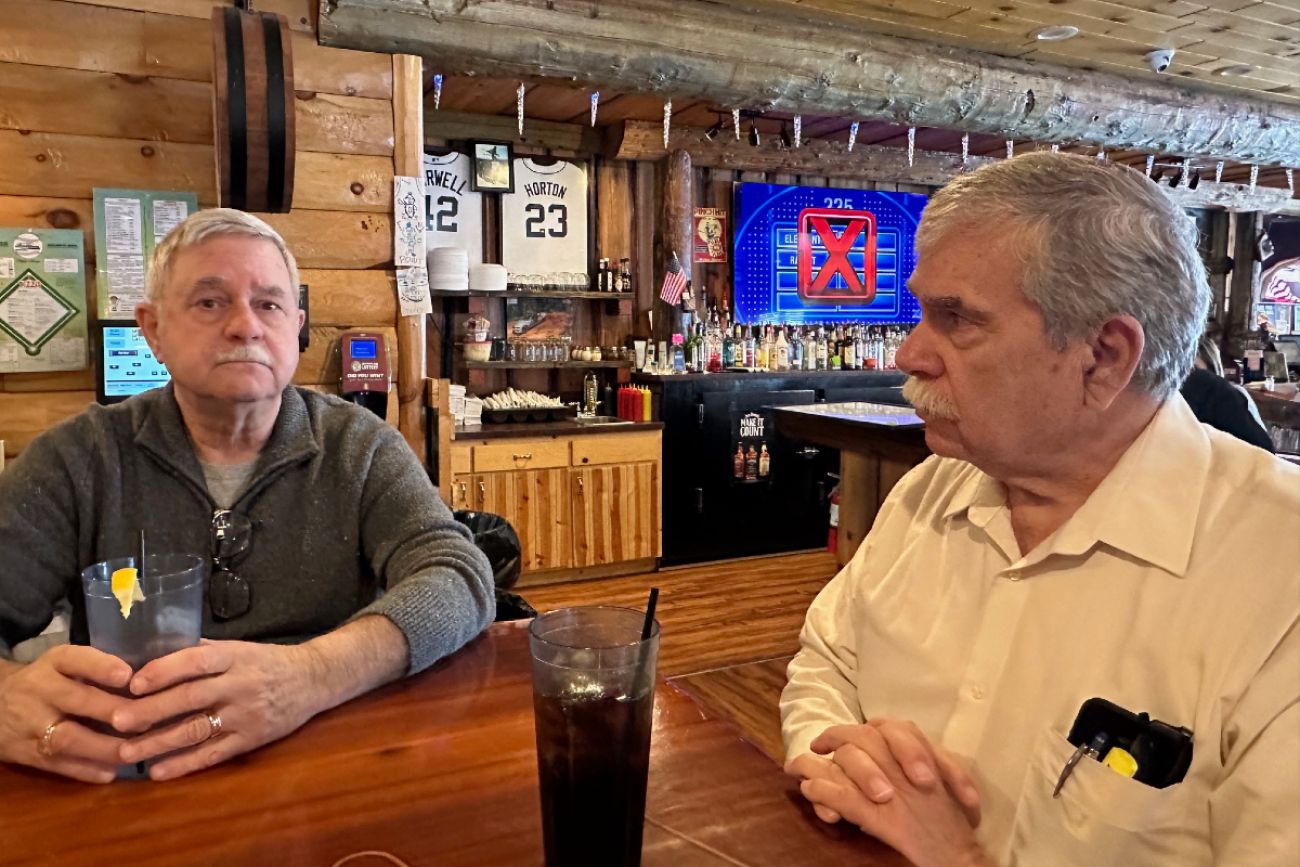 two men sit at a table in a bar