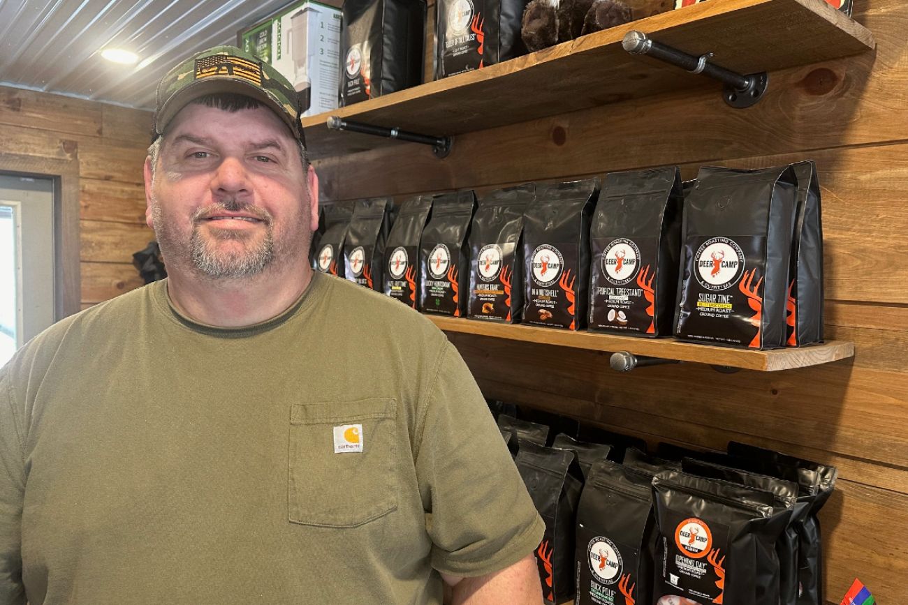 Man stands in front of shelf of coffee