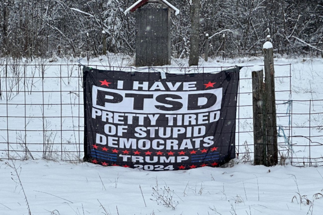Sign on fence reads: "I have PTSD. Pretty tired of stupid Democrats. Trump 2024"