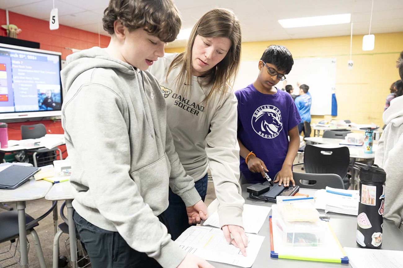 teacher standing next to student