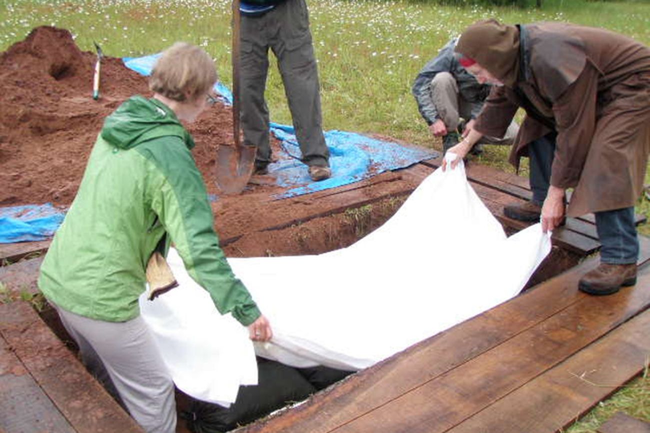 people putting a blanket in the ground