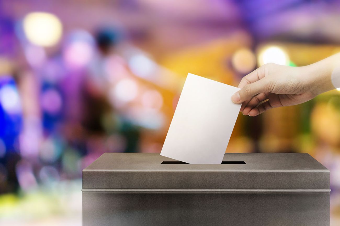 hand holding ballot paper for election vote concept at colorful background.