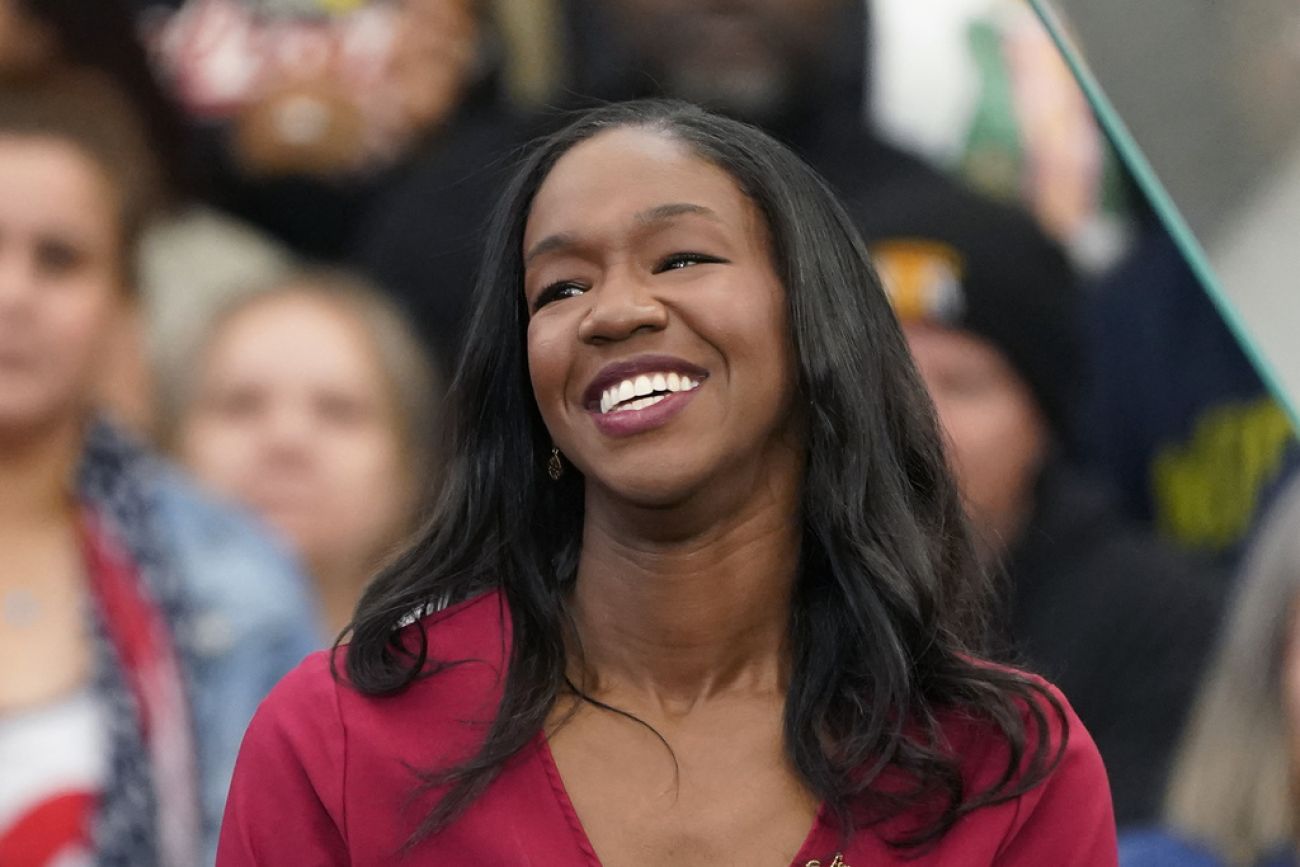 Kyra Harris Bolden is smiling. A crowd of people are behind her