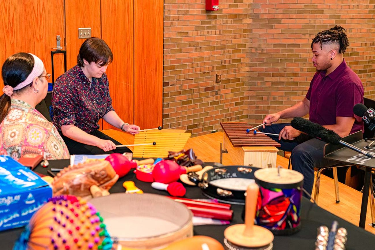 Three people sitting in a room, playing instruments