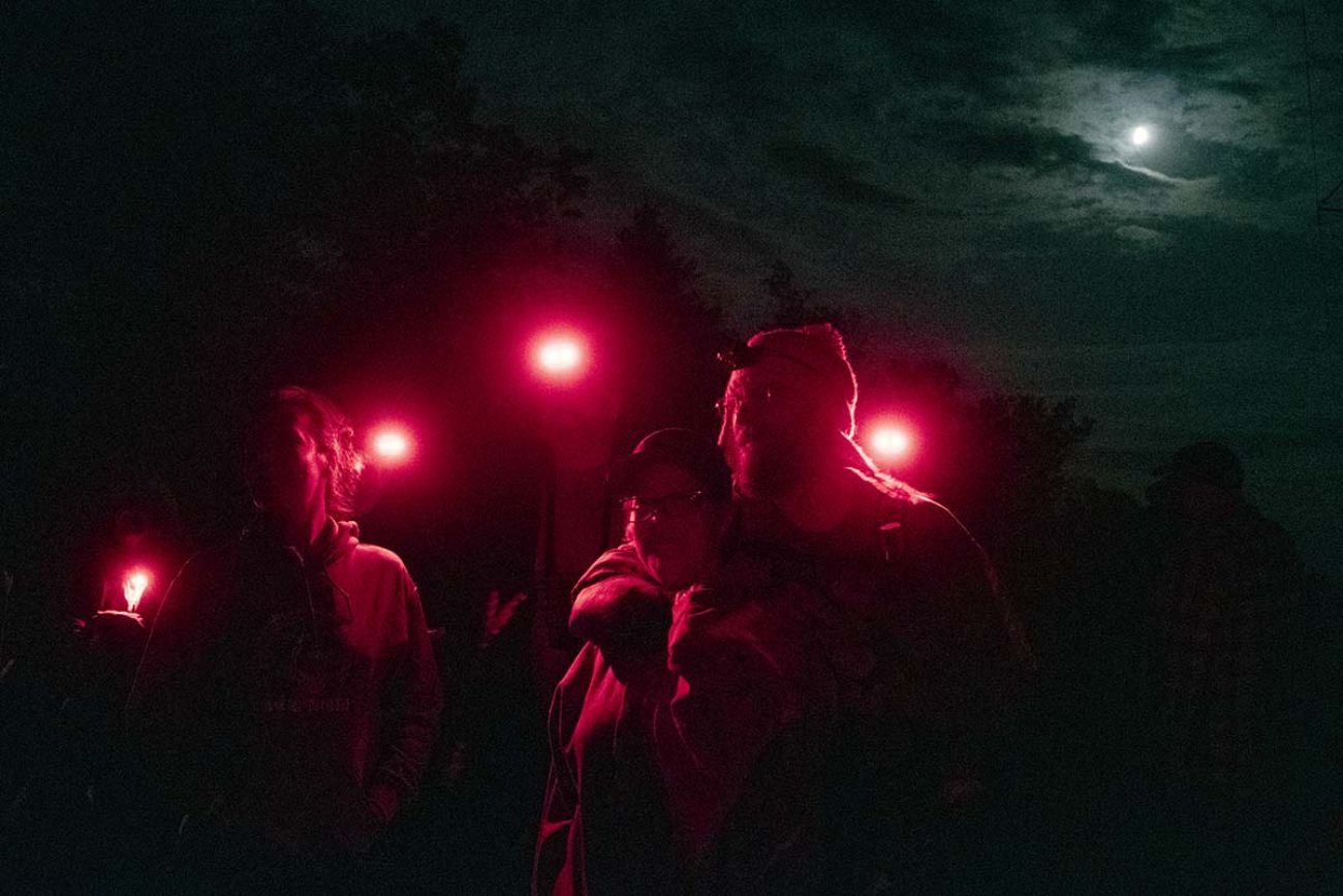 People walking at night. There faces are lit up by red lights