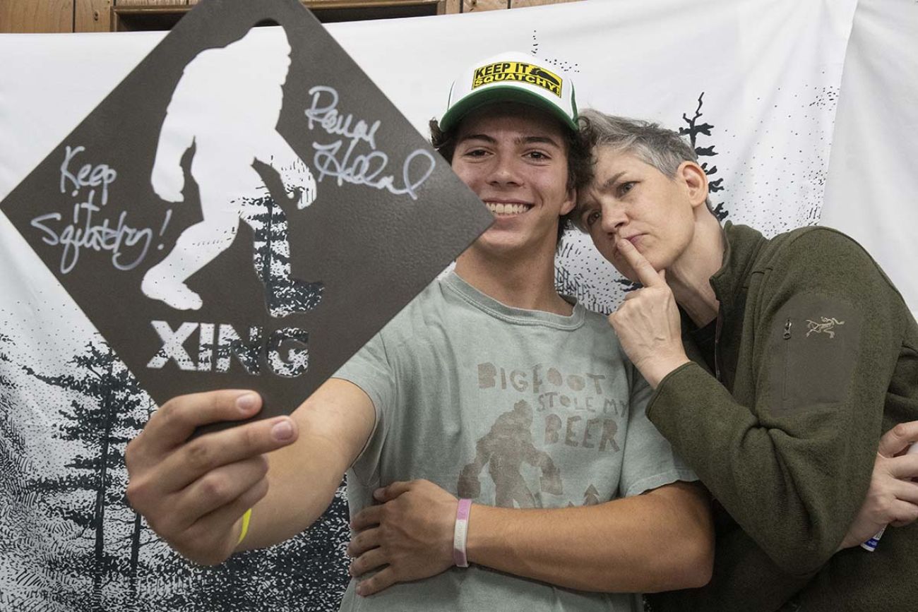 Two people holding up a Bigfoot crossing sign, talking a selfie