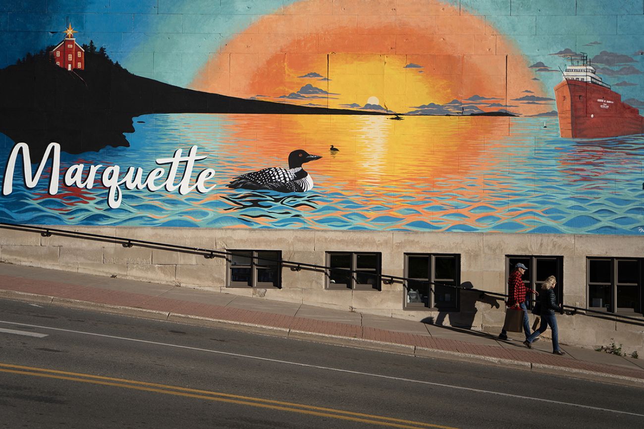 A mural of Marquette on the side of Trenary Toast. The mural shows a sunset, boat, lighthouse