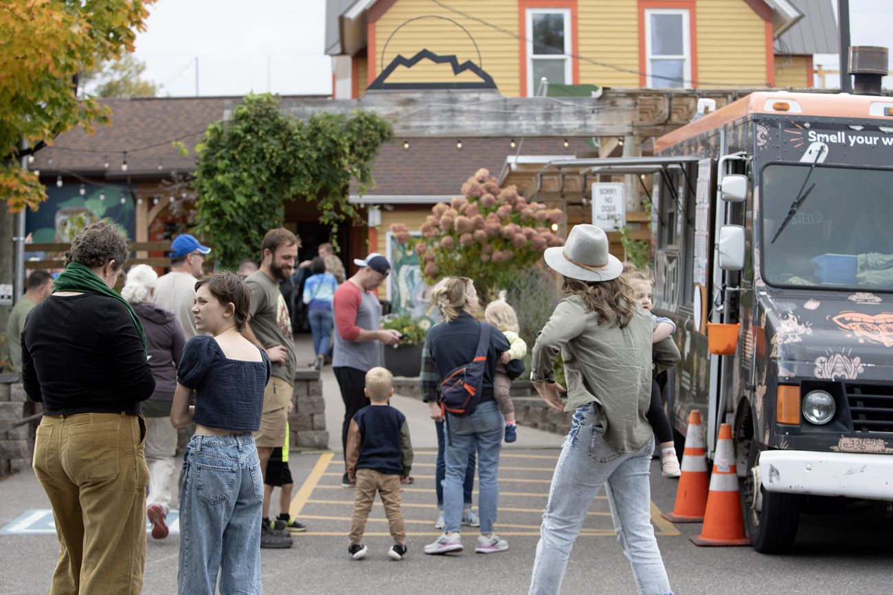 People standing in a parking lot, next to a food truck in Marquette, Mich