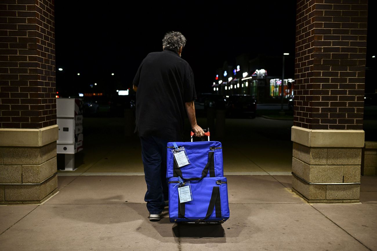 A poll worker has leaves with ballots in blue containers. He is taking it to Warren City Hall