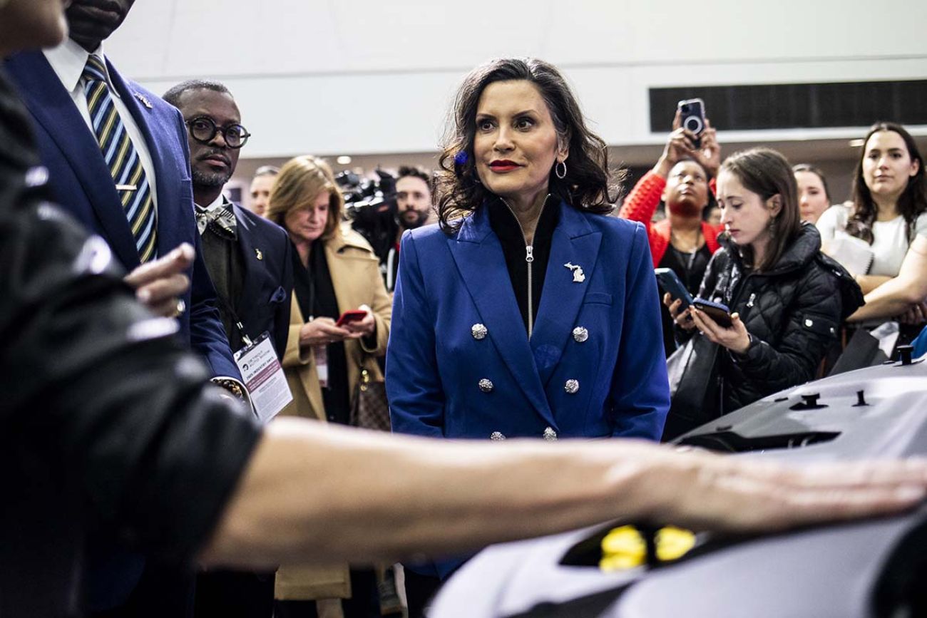 Michigan Gov. Gretchen Whitmer next to a car at the Detroit Auto Show.