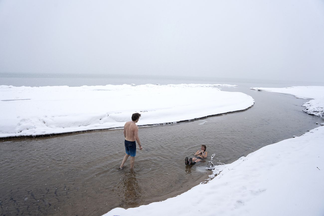 Two people in East Bay of Grand Traverse Bay in Michigan. It's snowy and icy outside.