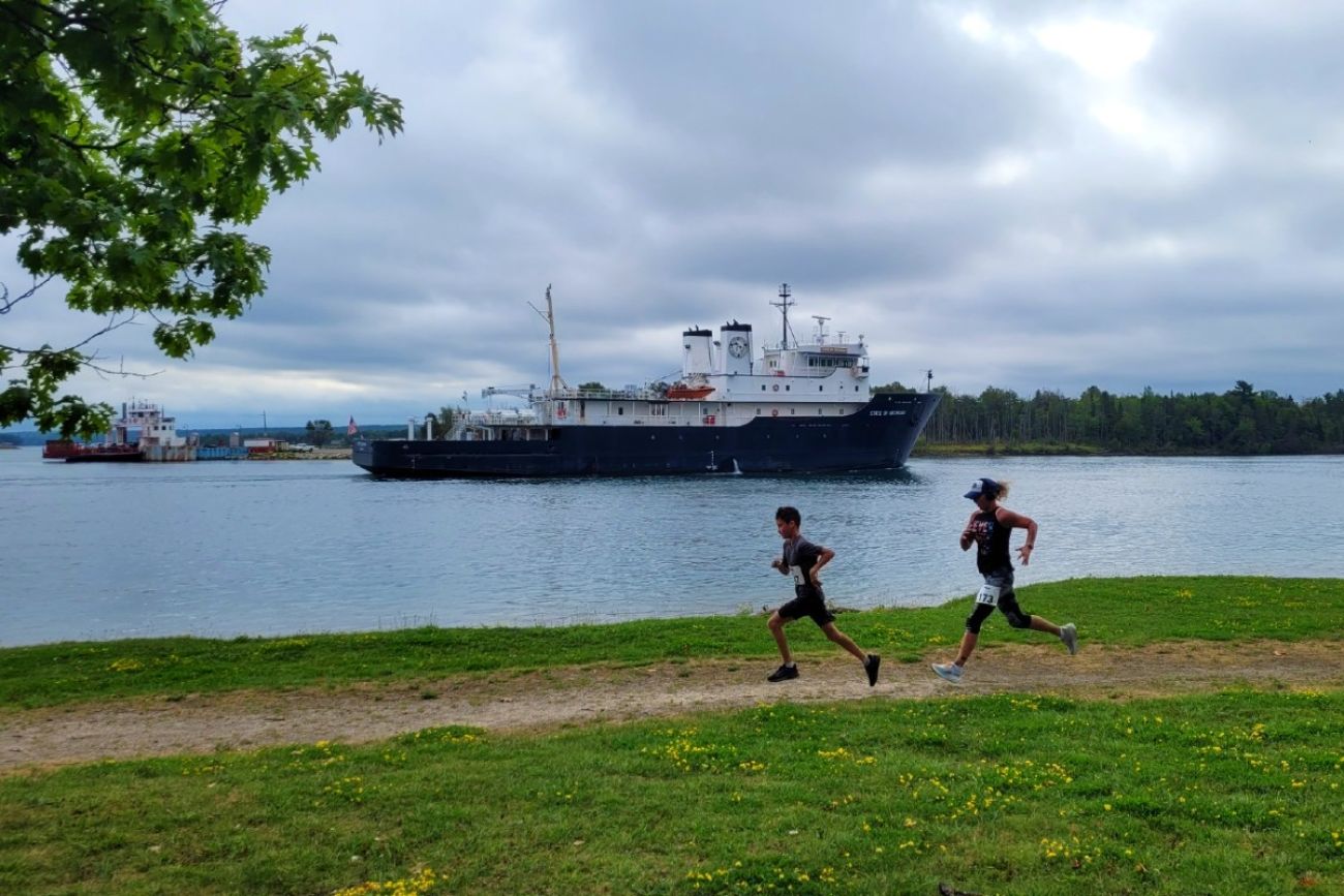 Runners race past a freighter