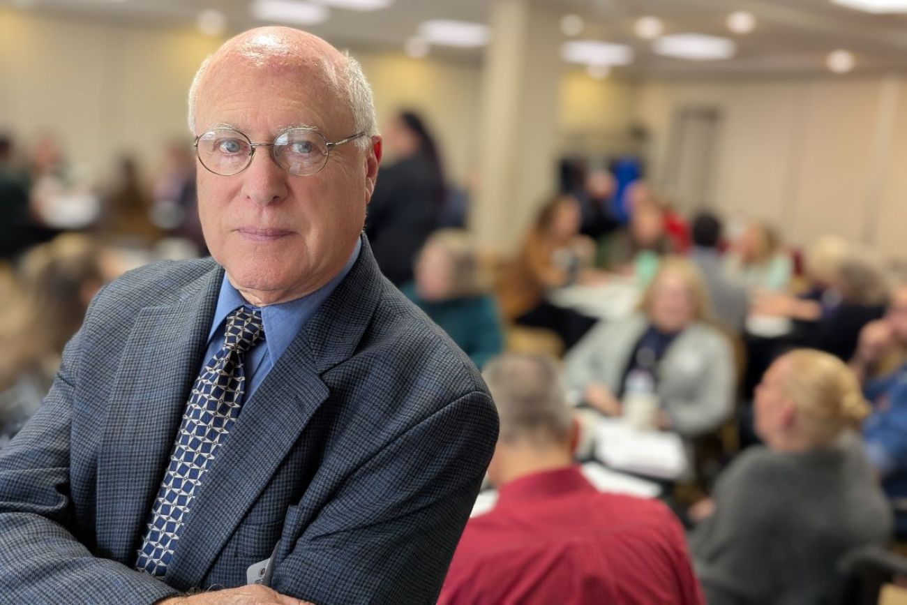 Richard Douglass in a room of older people in the background.