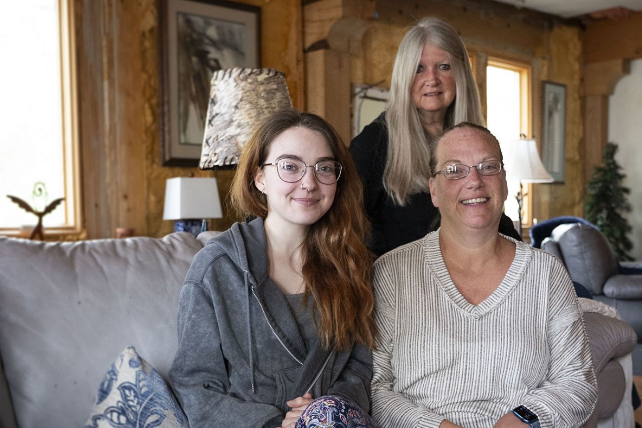 Family poses for a picture. They are sitting on the couch.