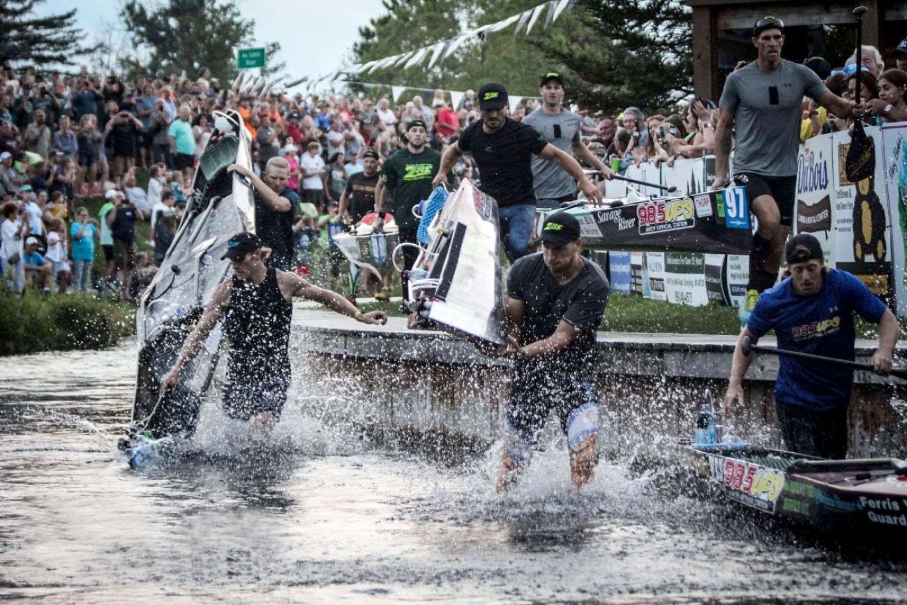 Racers carry their canoes through a shallow part of the Au Sable River during a race