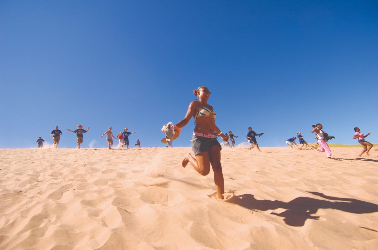 People run down a sandy dune at Sleeping Bear Dunes National Lakeshore
