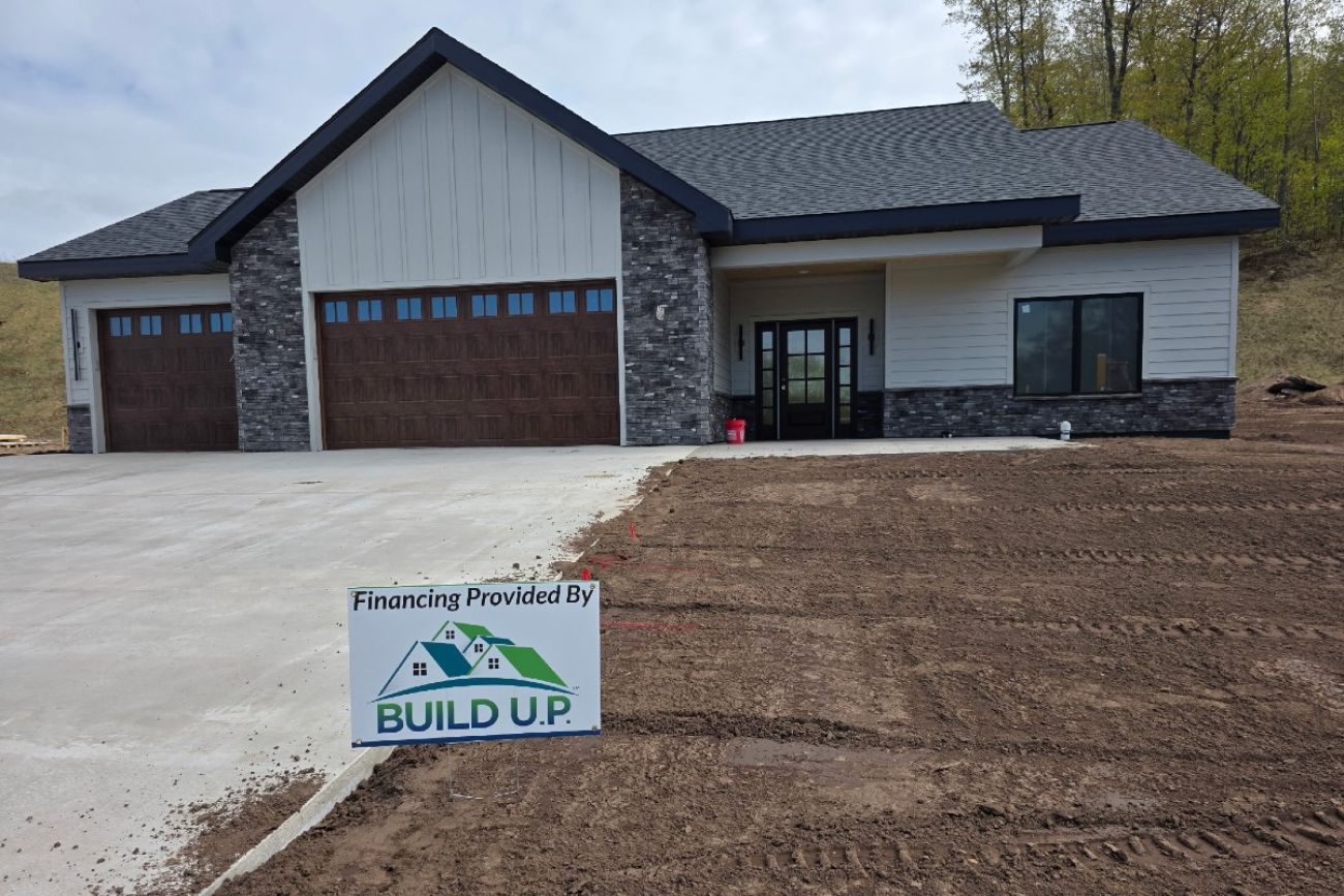 A home is seen with a concrete driveway and an unfinished yard
