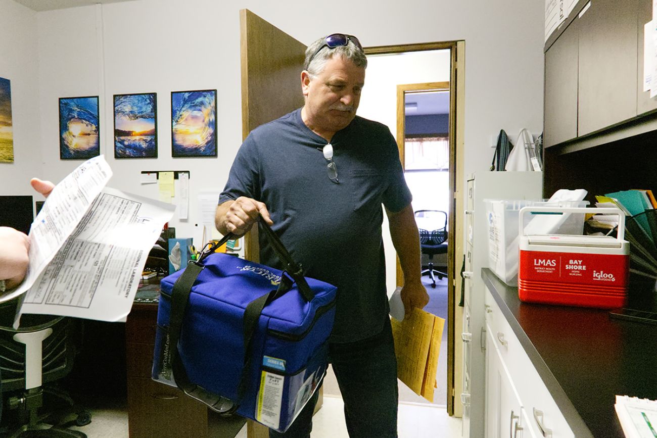 John Huffman carries a blue container of water samples.