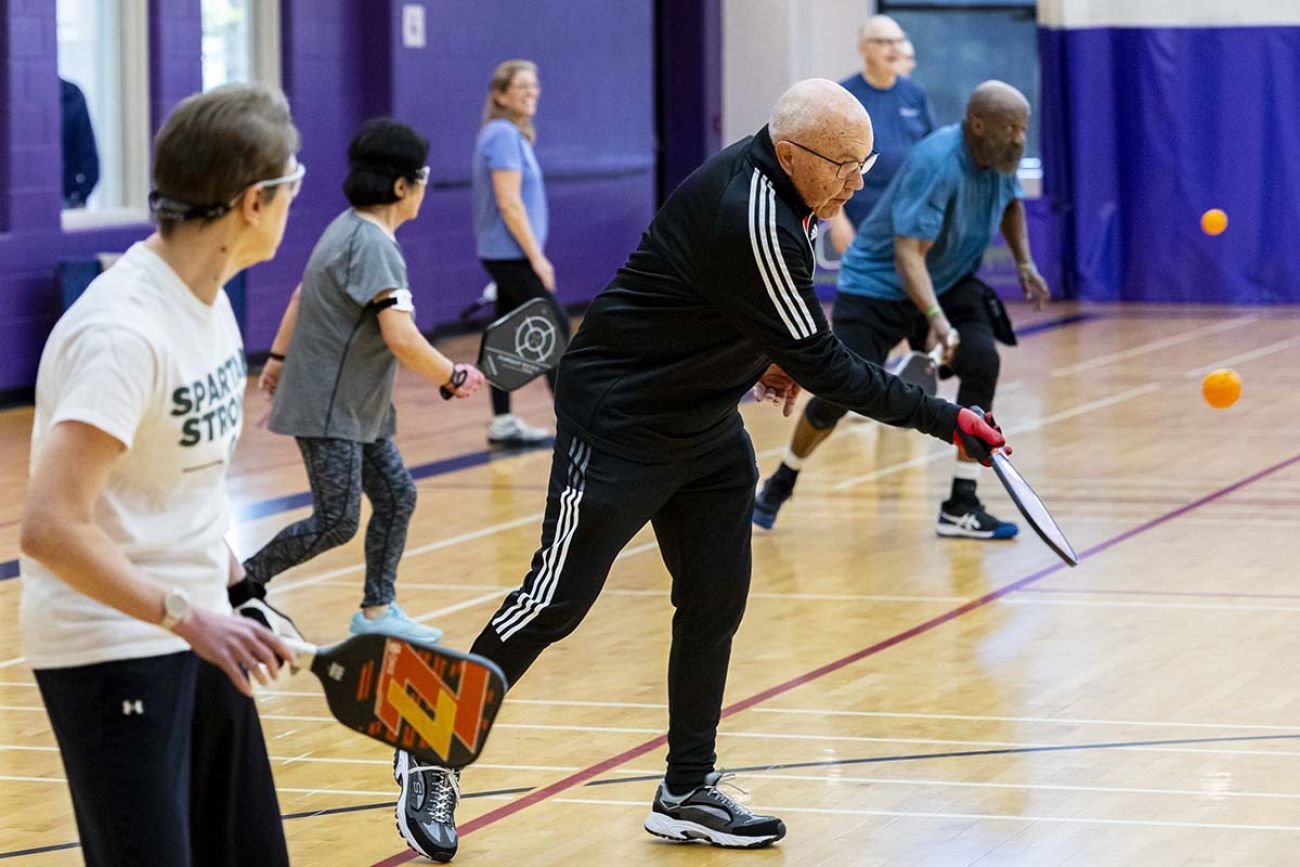 Hans Spata and others play pickleball in an indoor gym.