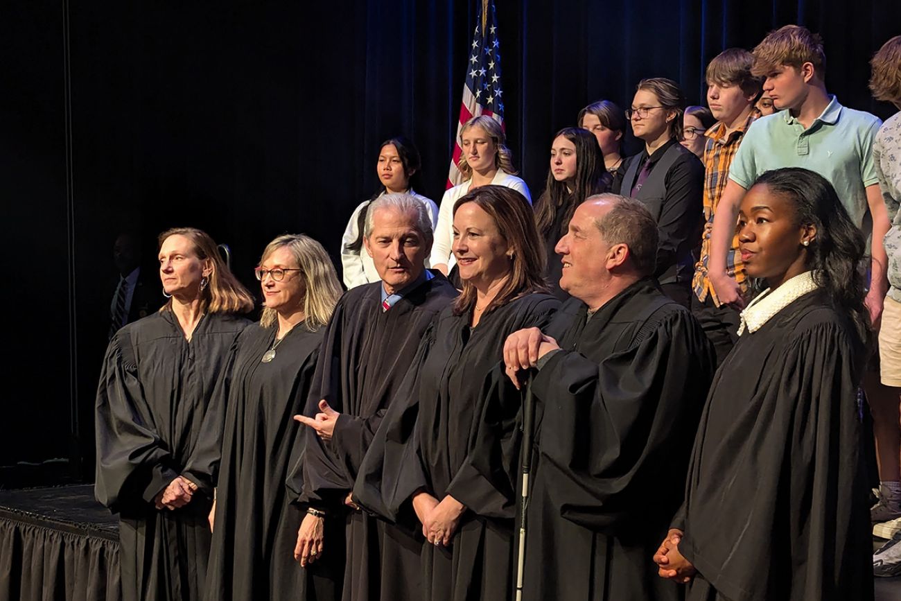 Michigan Supreme Court justices stand in a row. Students are behind them.